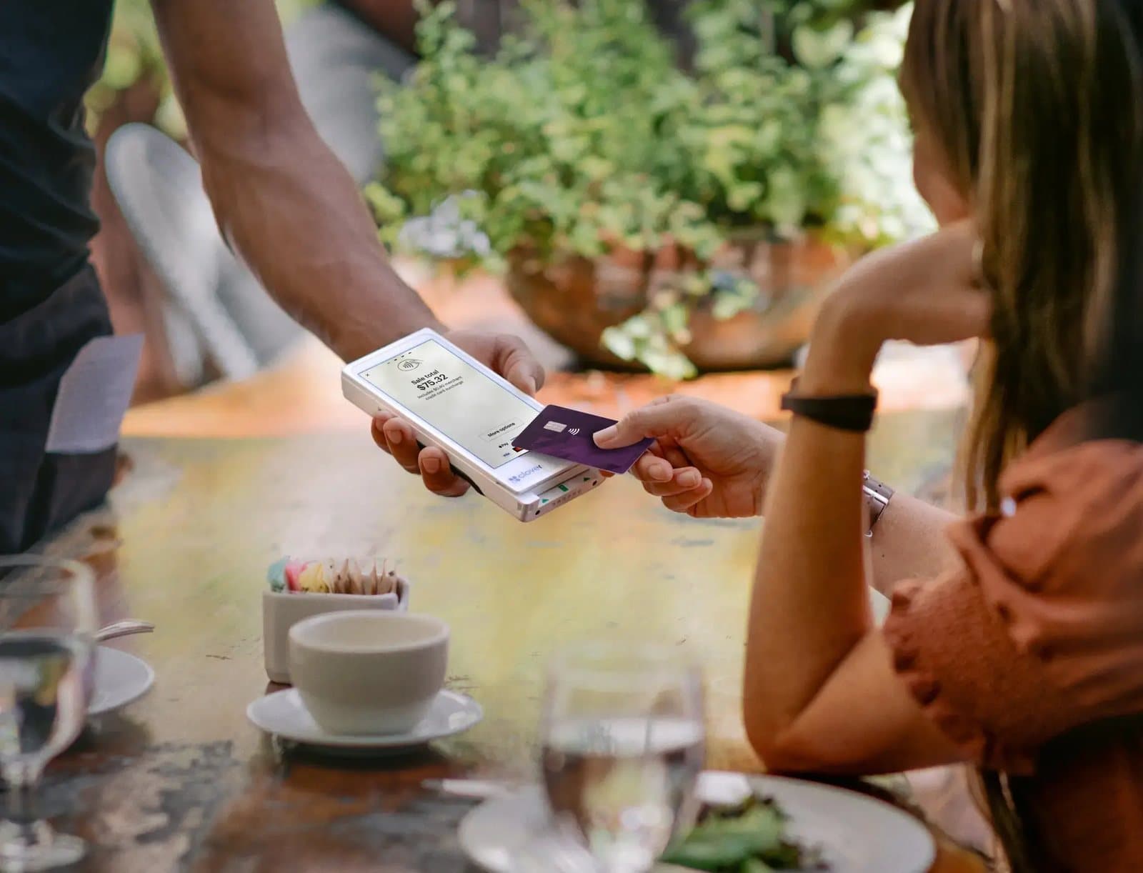 A restaurant guest paying at the table with a card on a handheld terminal